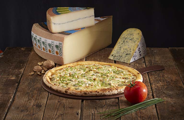 Pizza 3 fromages du Jura entourée des ingrédients qui la composent : Comté AOP, Bleu de Gex AOP, Morbier AOP