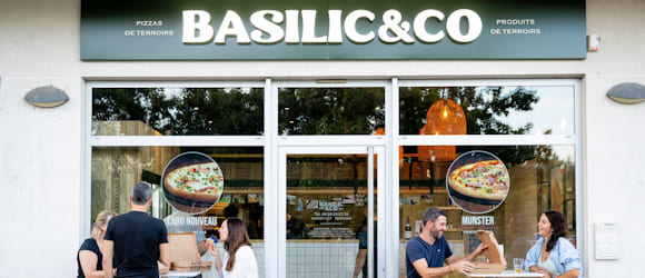 Façade de la pizzeria Basilic & Co Brignais, avec des clients mangeant sur des mange-debout devant.